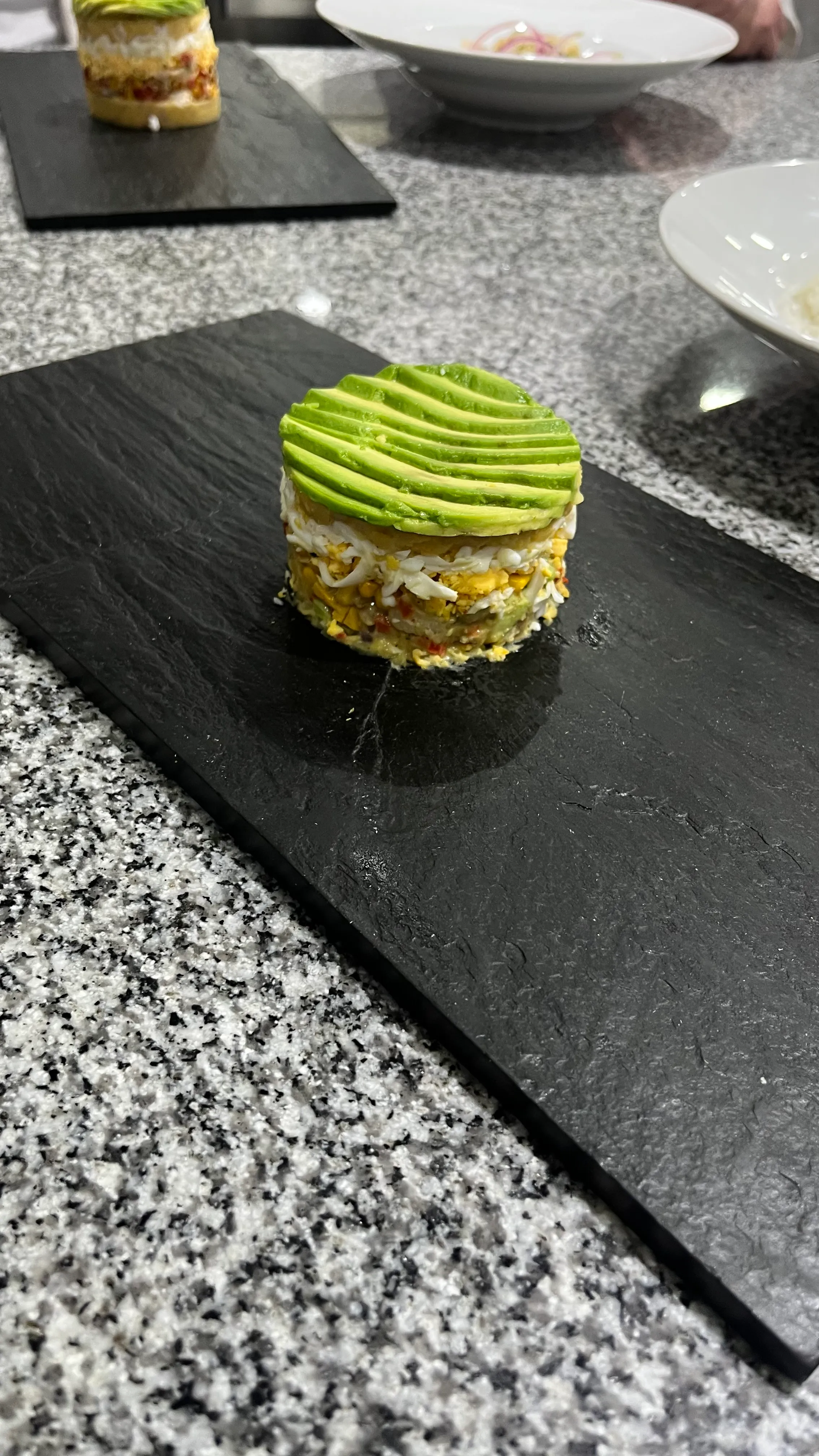 A plated dish by Lucía: a layered stack topped with sliced avocado